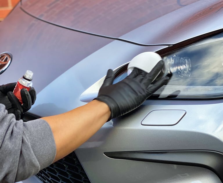 Gloved hands applying product to headlight